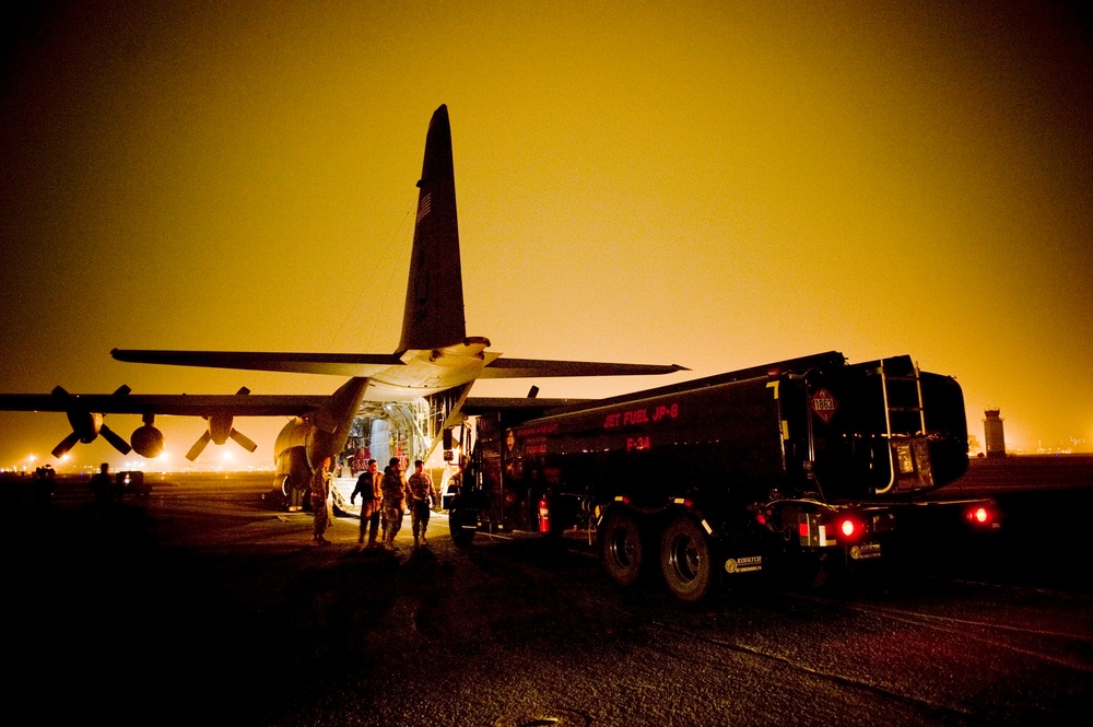 A fuels truck pulls up to a C-130H Hercules aircraft to be loaded.