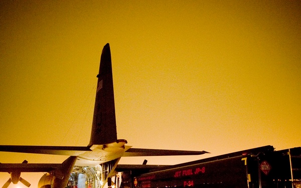 A fuels truck pulls up to a C-130H Hercules aircraft to be loaded.
