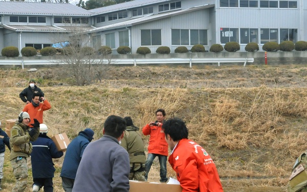 Airmen work alongside a team of Japanese medical workers to unload food, water and medical supplies.