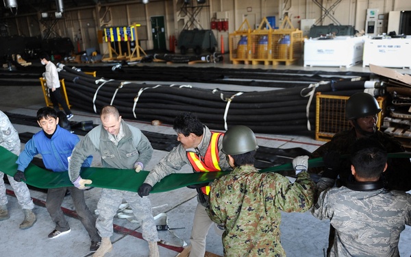 U.S. airmen, members of the Japan Ground Self-Defense Force and various Japanese civilian agencies load water hoses.