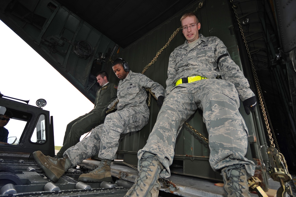 U.S. Air Force airmen load communication equipment into a C-130 Hercules aircraft.