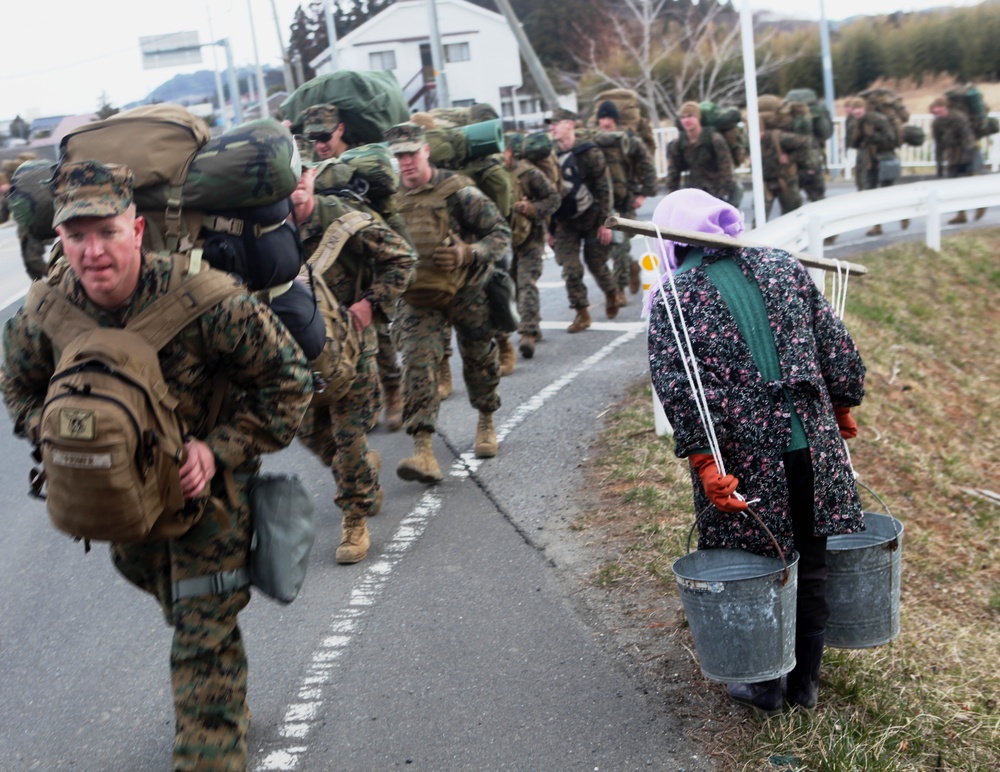 A local woman carrying water bows in thanks to Marines who are on the way to assist with Operation Field Day.
