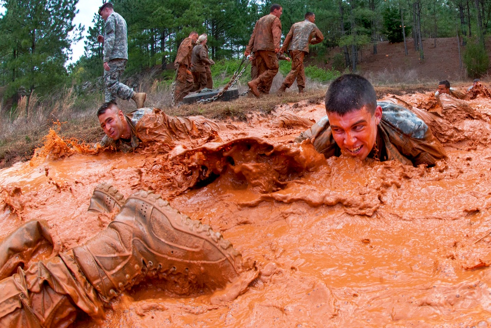 U.S. Army 1st Lt. Andrew McKinley crawls through a muddy obstacle.