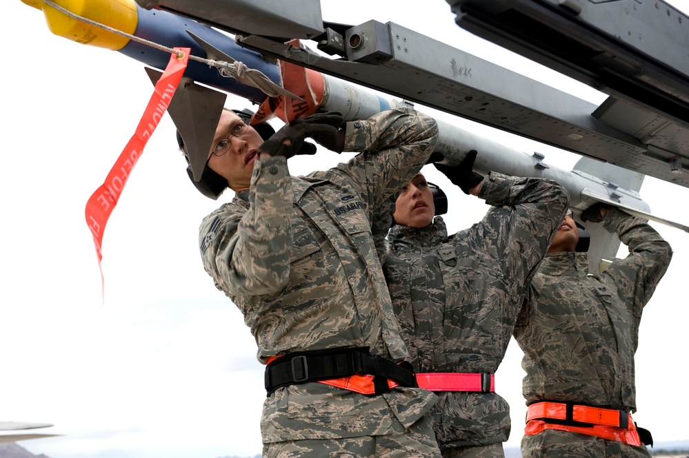Senior Airman Lucas Wolf, Airman 1st Class Amanda Schreckengost and Staff Sgt. Jason Spears load an Air Intercept Missile-9M Sidewinder onto an F-16 Fighting Falcon aircraft.