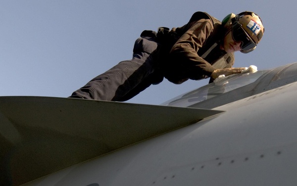 Seaman Bryan Domingue cleans the canopy on an F/A-18F Super Hornet aircraft