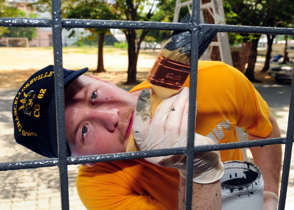 Petty Officer 2nd Class Jason Barcellos paints part of the Muang Phuket School in Chalong, Thailand.