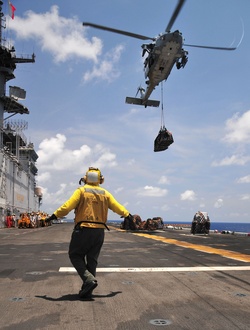 Petty Officer 3rd Class Rodolfo Lopez signals an MH-60 Seahawk helicopter.