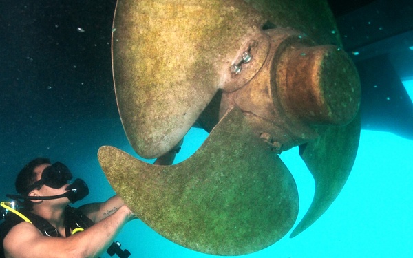 Petty Officer 3rd Class Bryan Myers maneuvers around a ship's propeller.
