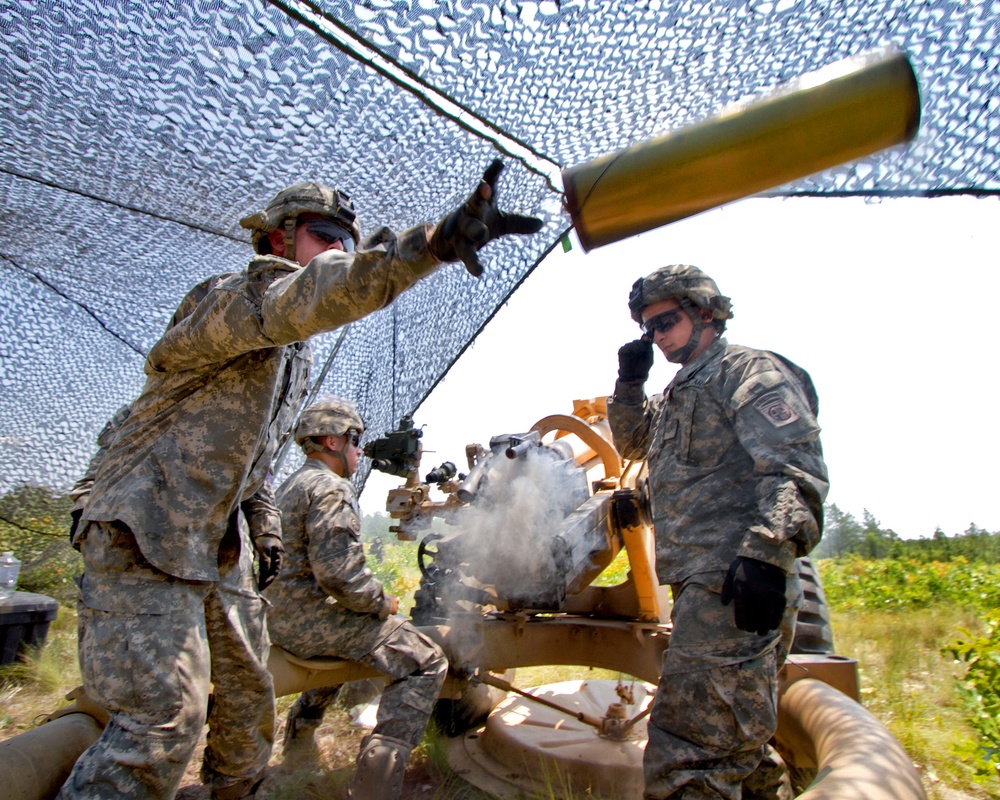 Sgt. Adam Phillips tosses an empty canister from an M119A2 105mm howitzer.