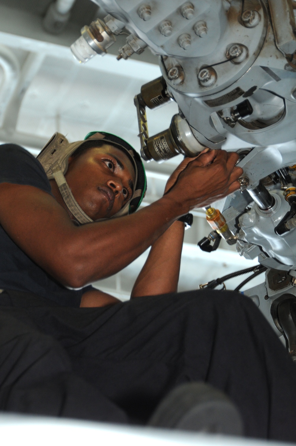 Petty Officer 3rd Class Gavin Persaud cleans and inspects the rotor assembly of an MH-60S Seahawk helicopter.