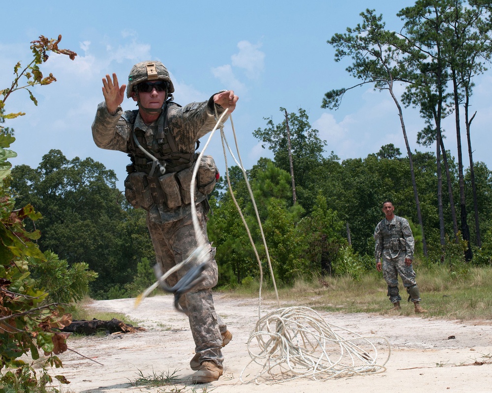 A U.S. Army soldier throws a grappling hook to clear a potential mine field.