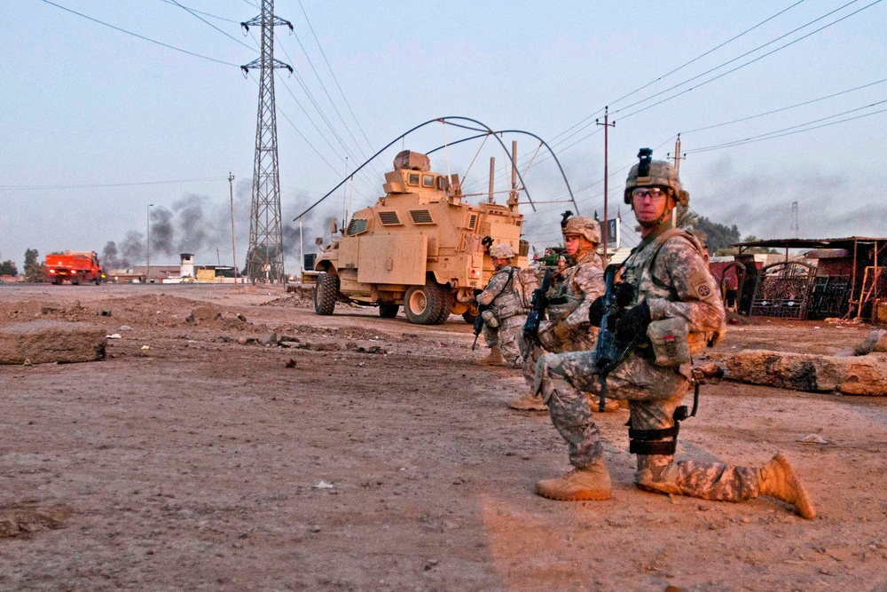U.S. Army military policemen take a knee during a patrol along a road outside Camp Taji.