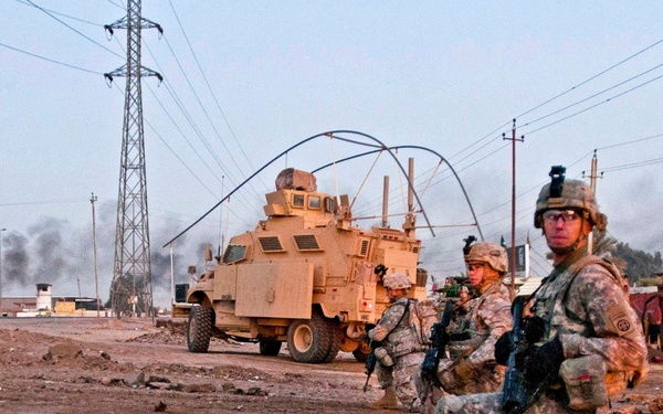 U.S. Army military policemen take a knee during a patrol along a road outside Camp Taji.