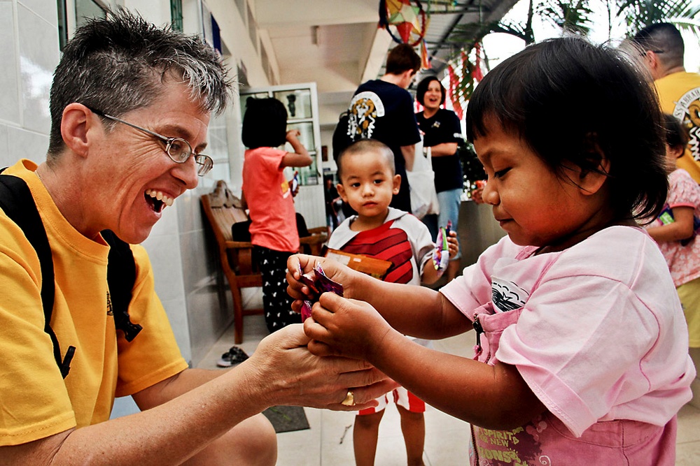 Master Chief Petty Officer Susan Whitman shares candy with a young girl during a community service project.