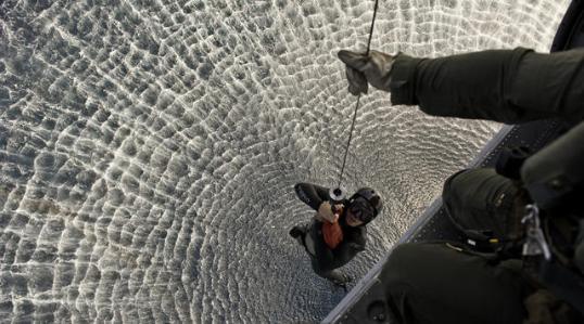 A U.S. Navy sailor gets a lift to an MH-60S Sea Hawk helicopter.
