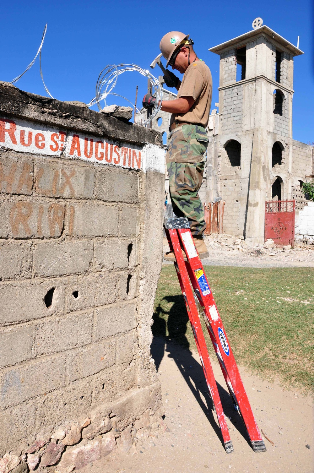 Petty Officer 2nd Class Michael McAfee mounts a stake into the security wall surrounding Dispensaire De Caracol.