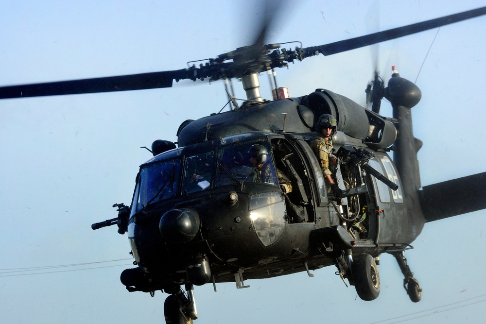 A U.S. Army crew chief observes the horizon from the side door of a UH-60 Black Hawk helicopter.