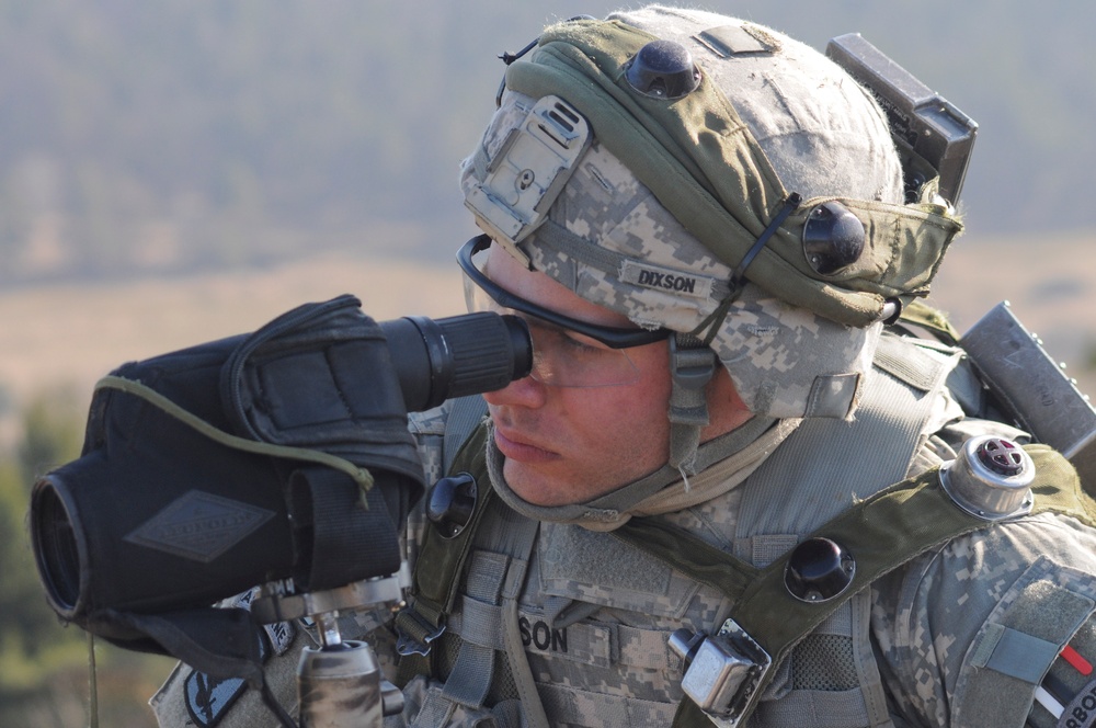 Spc. Zachary Dixson uses a spotting scope to watch for simulated enemy combatants.
