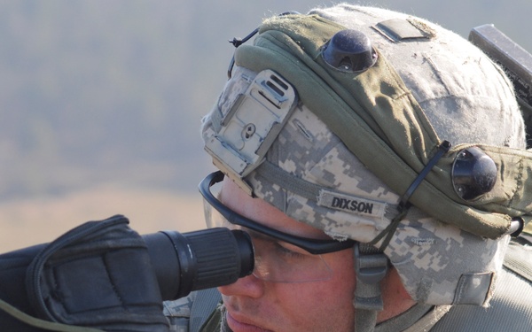 Spc. Zachary Dixson uses a spotting scope to watch for simulated enemy combatants.