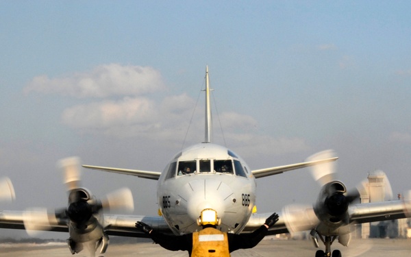 Airman Mark Jimenez signals the pilots of a P-3 Orion aircraft before takeoff.