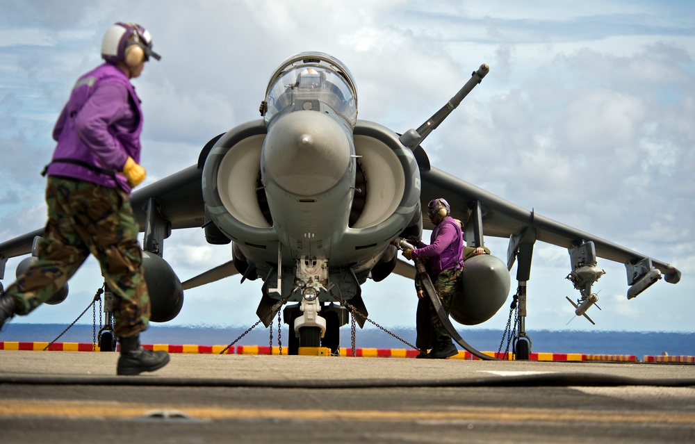 A flight deck crewman refuels an AV-8B Harrier
