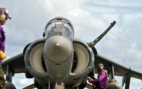 A flight deck crewman refuels an AV-8B Harrier