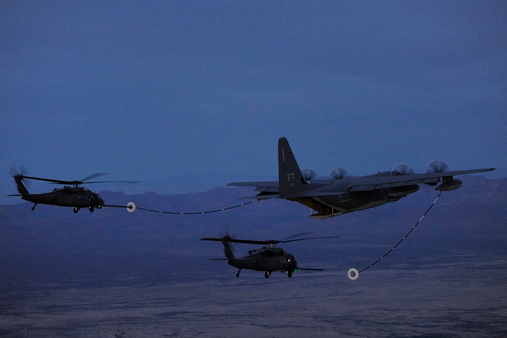 A U.S. Air Force HC-130J Combat King II aircraft conducts aerial refueling with two HH-60G Pave Hawk helicopters