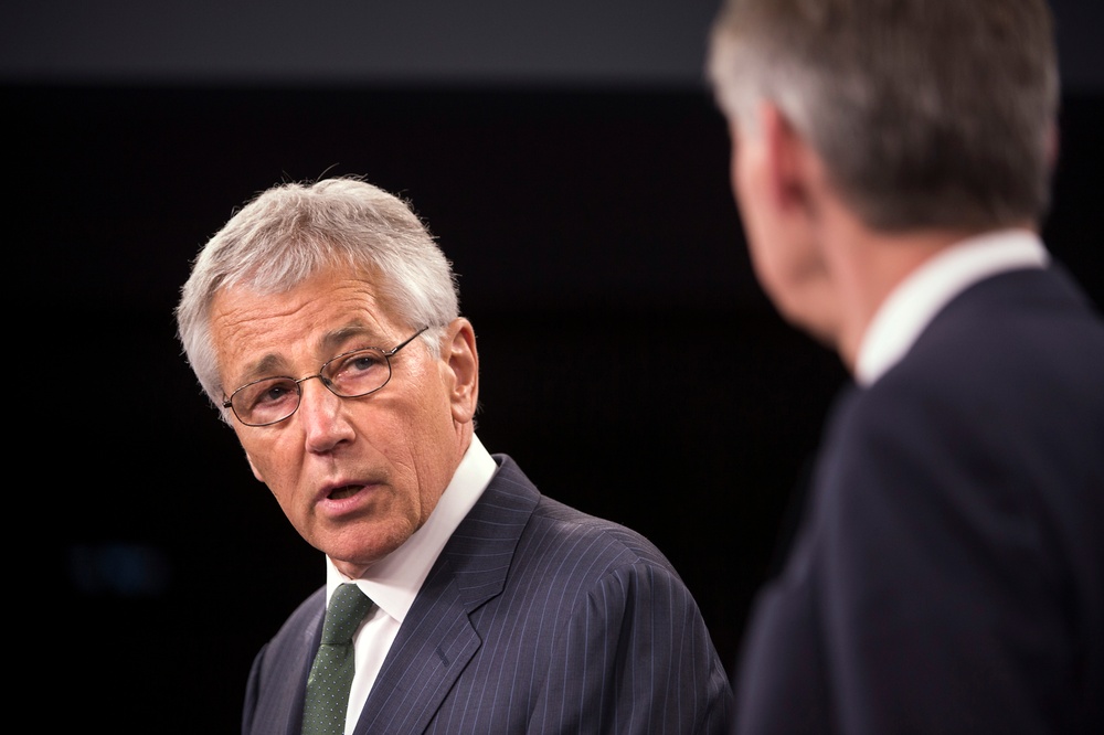 Secretary Hagel looks at the United Kingdom's Secretary of State for Defence Phillip Hammond as he describes their earlier meeting to reporters