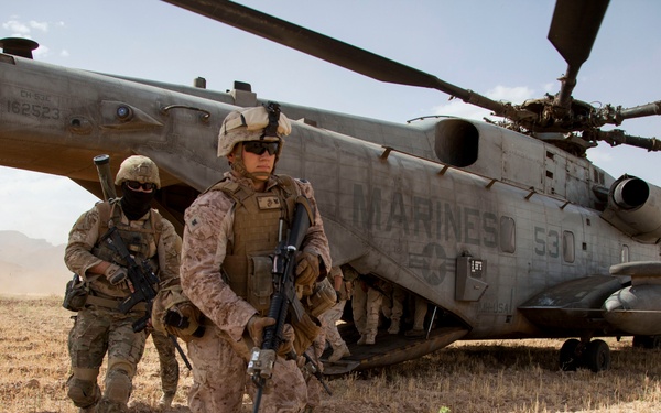 Petty Officer 3rd Class Cameron Kirk exits a U.S. Marine Corps CH-53E Super Stallion helicopter