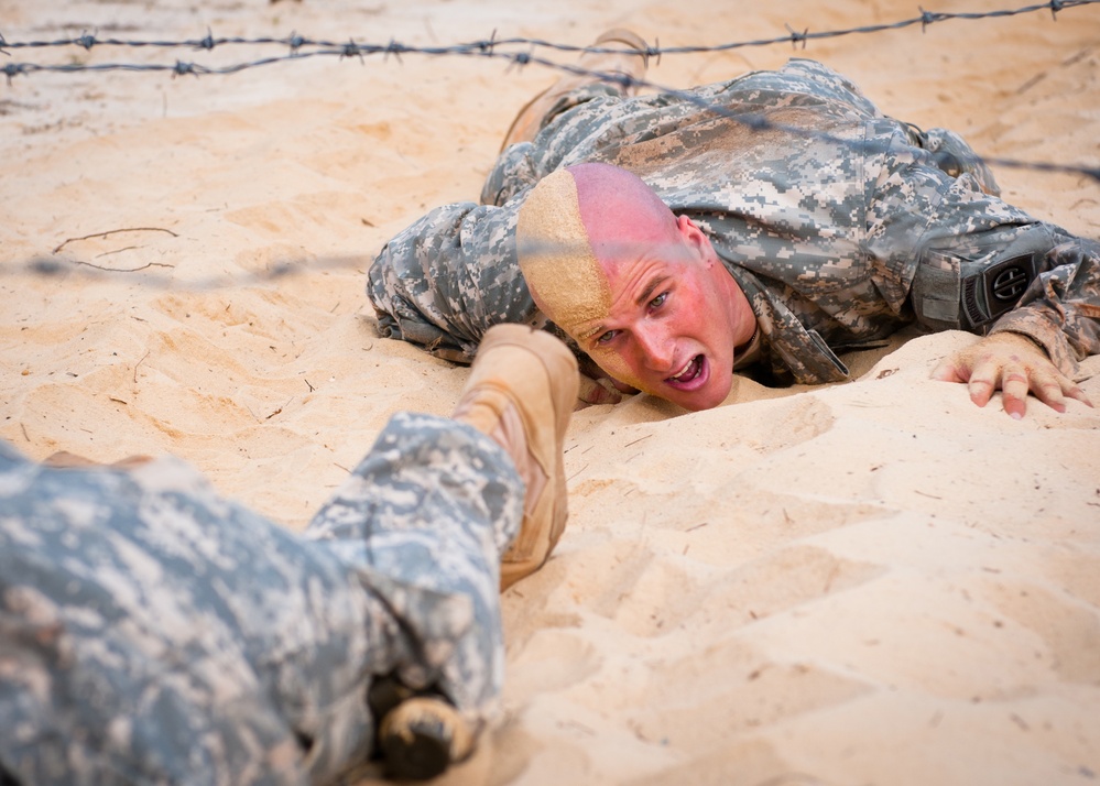 A soldier slithers through a sand pit on the Air Assault School obstacle course at Fort Bragg