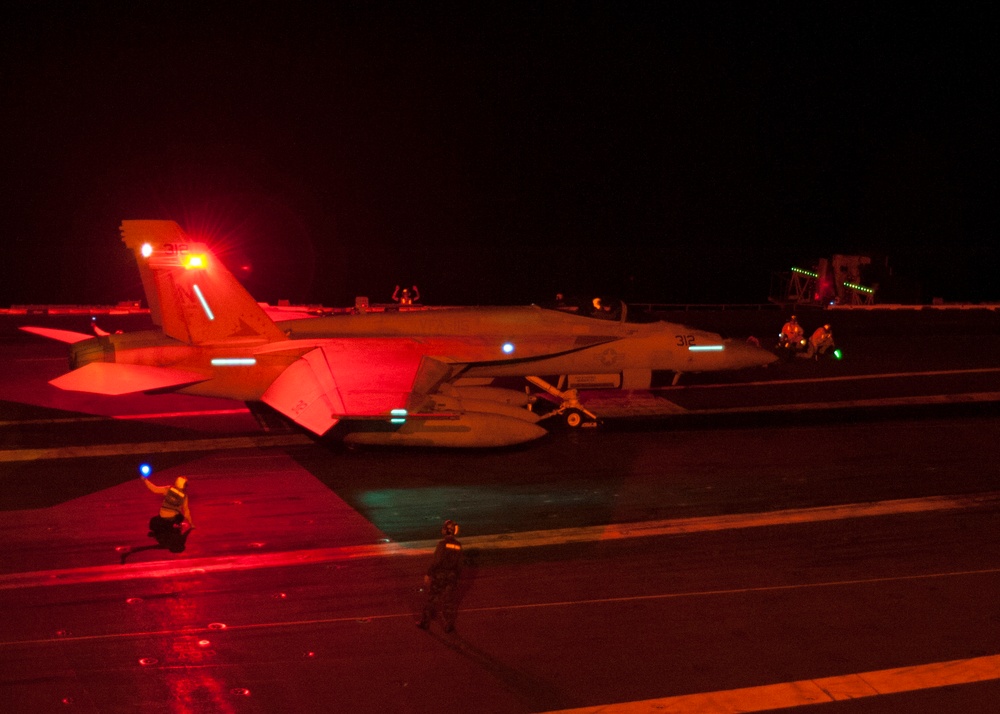 A U.S. Navy F/A-18F Super Hornet is prepared for a nighttime catapult launch