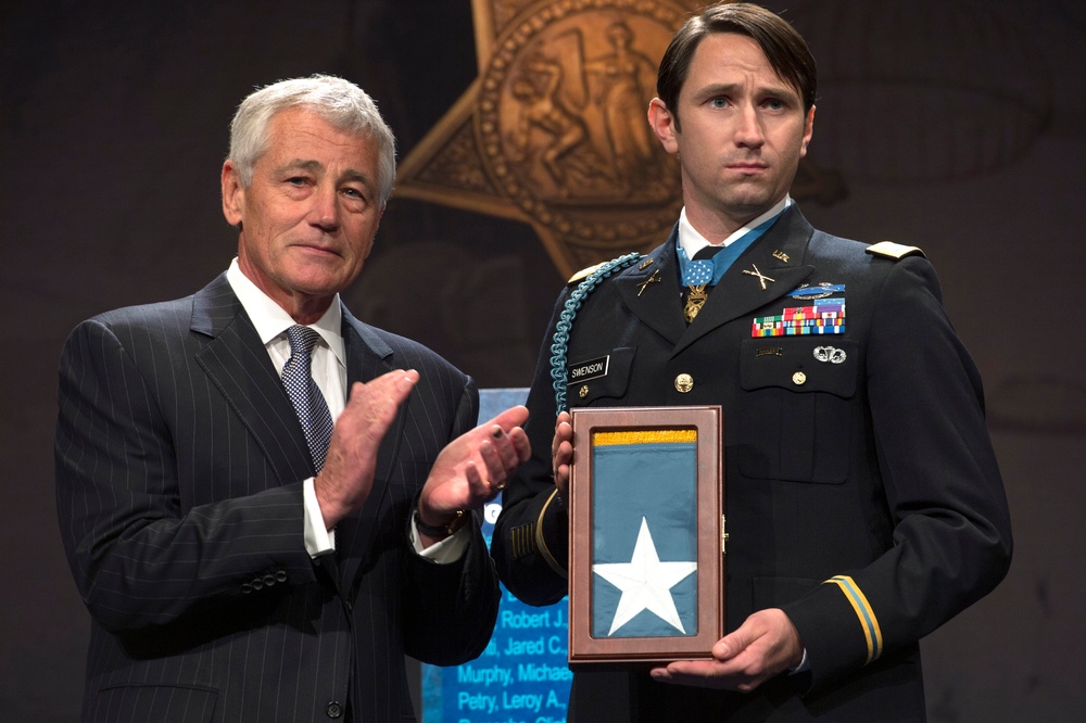 Secretary Hagel applauds after presenting the Medal of Honor flag to former Army Capt. William Swenson
