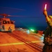 AD2 Keith Gonzales signals to MH-60R Sea Hawk helicopter pilots with illuminated batons