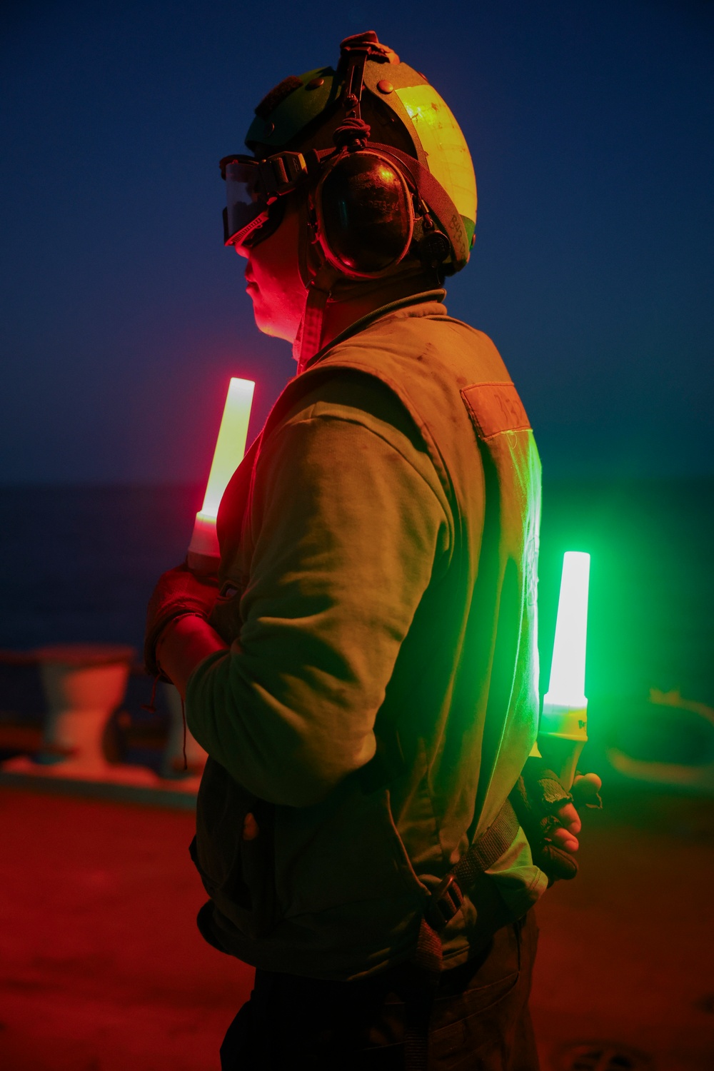 AD2 Keith Gonzales uses illuminated signal batons on the USS Bulkeley's flight deck