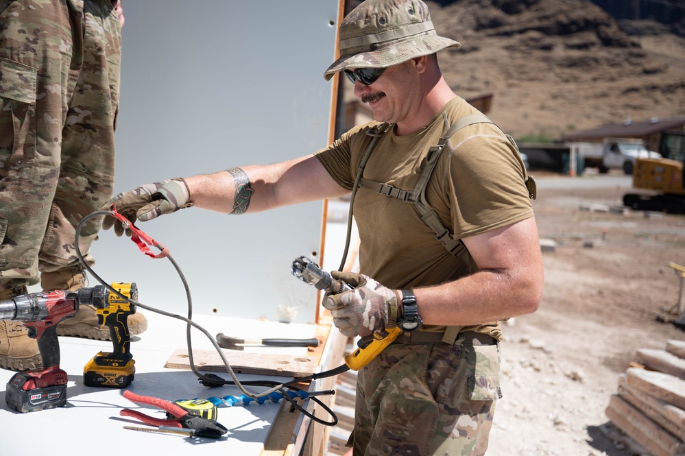Airmen drill holes in a building for electrical wiring in Hawaii