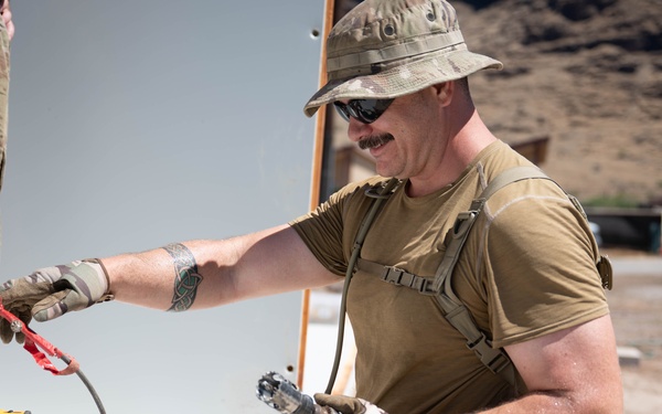 Airmen drill holes in a building for electrical wiring in Hawaii