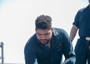 USS Mitscher (DDG 67) Sailor greets working dog