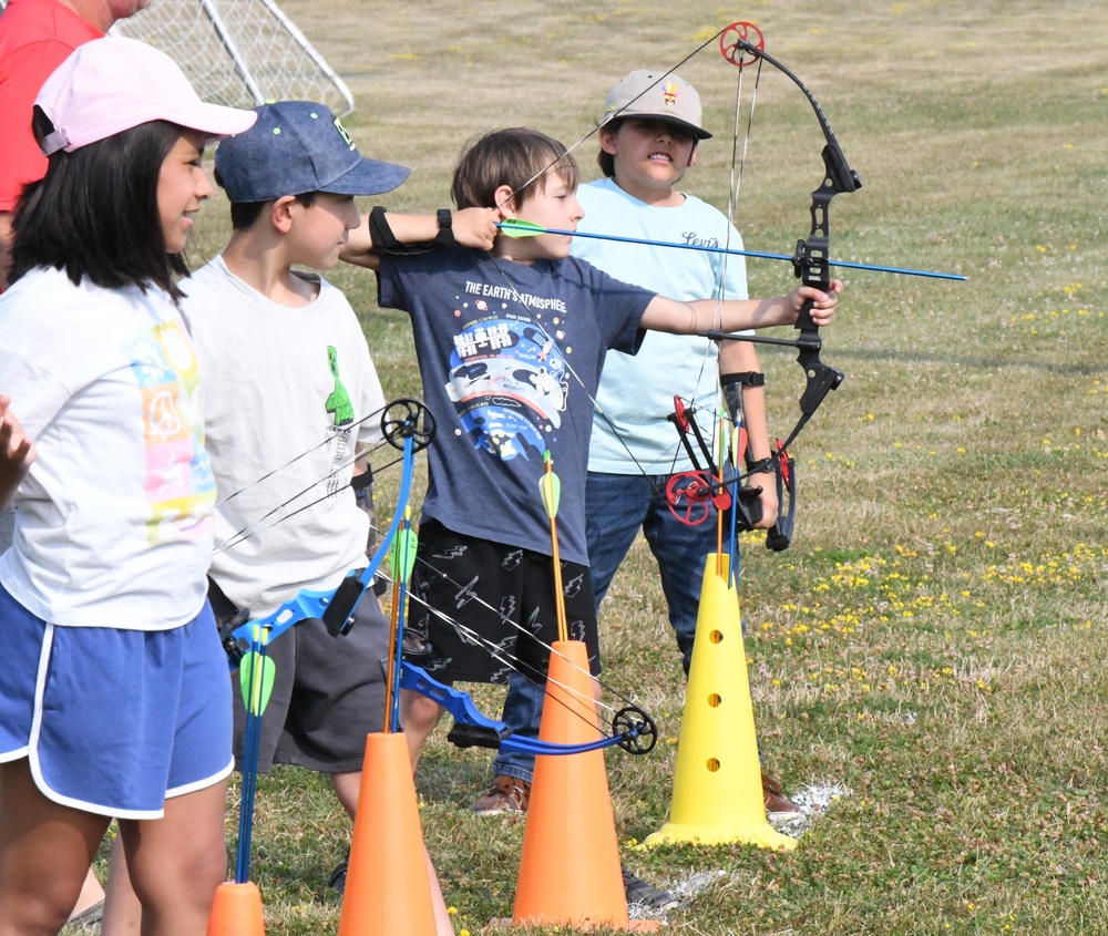 One flag football camp attendee helps another learn how to throw the ball during a practice