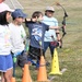 One flag football camp attendee helps another learn how to throw the ball during a practice