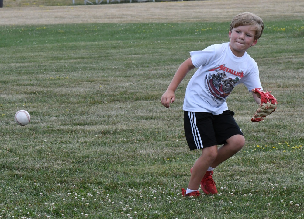 One flag football camp attendee helps another learn how to throw the ball during a practice