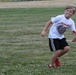One flag football camp attendee helps another learn how to throw the ball during a practice