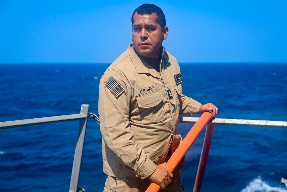 PSc Gilberto Infante steadies a fire hose during a fresh water wash down