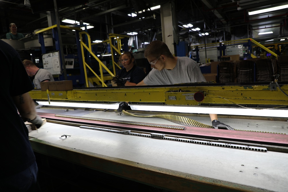 Lake City Army Ammunition Plant employee inspecting a row of linked ammo prior to packaging.