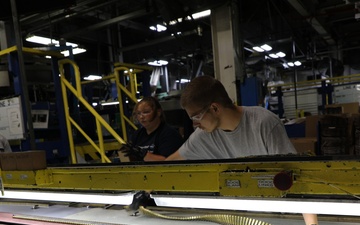 Lake City Army Ammunition Plant employee inspecting a row of linked ammo prior to packaging.