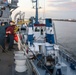 Sailors toss a mooring line to a tug boat during a sea-and-anchor