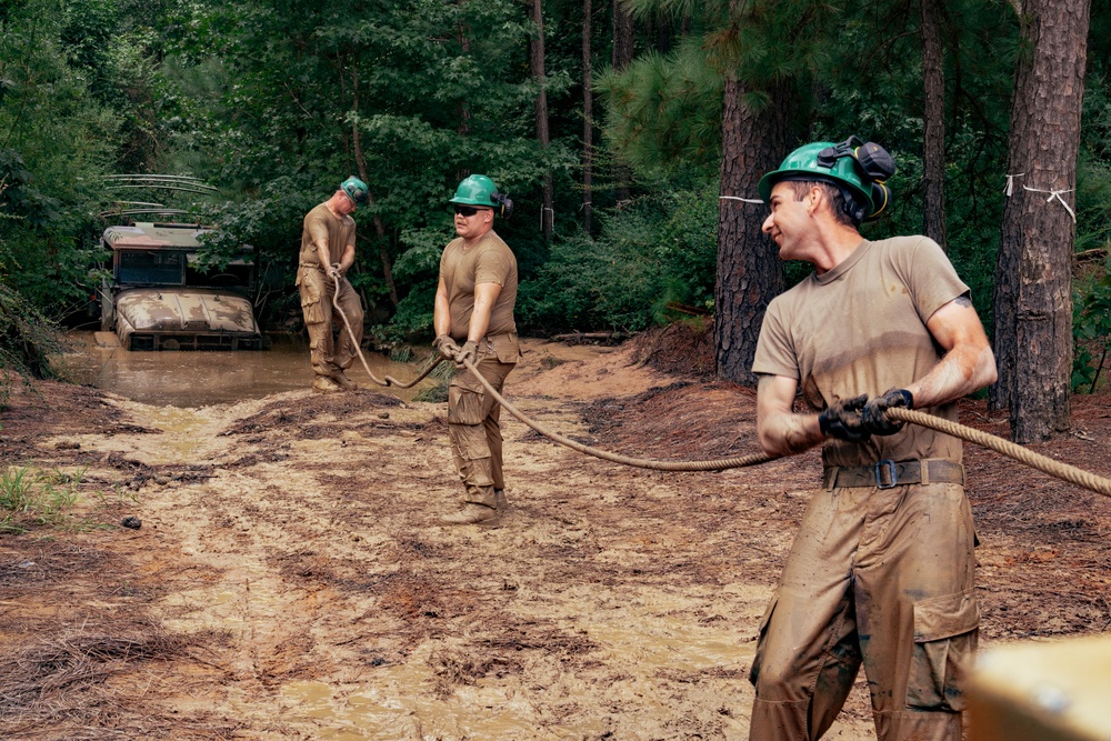 U.S. Army Soldiers pull cable while rigging a vehicle stuck in the mire pit during the Wheeled Vehicle Recovery Operations Course held at the 139th Regional Training Institute in Fort Bragg, NC, August 8, 2025