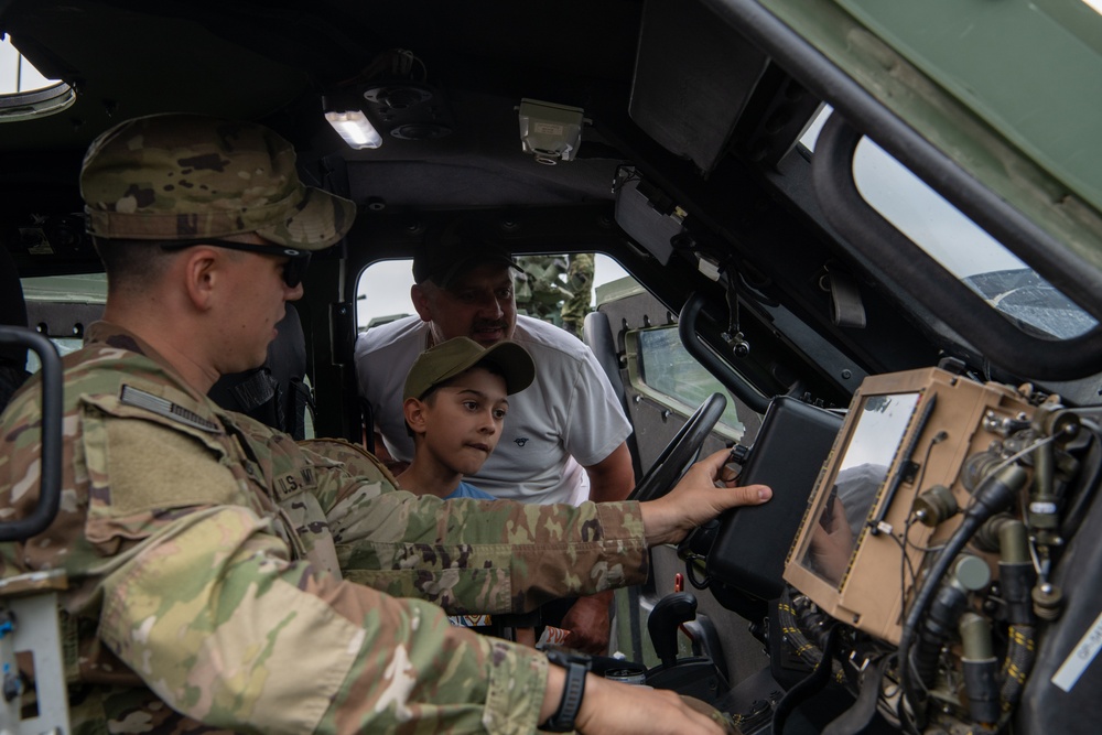 U.S. Army Soldier explains vehicle system to Polish boy and father