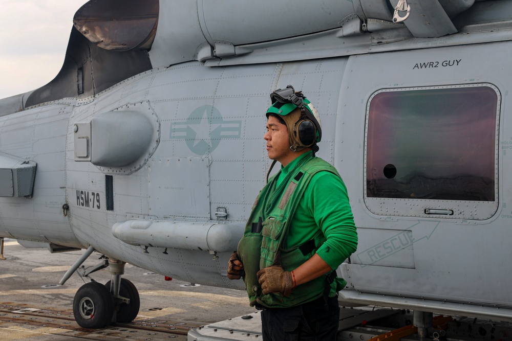 AD2 Keith Gonzales stands ready to support the launch of an MH-60R Sea Hawk helicopter