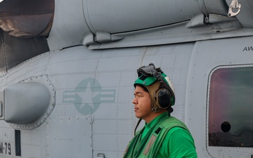 AD2 Keith Gonzales stands ready to support the launch of an MH-60R Sea Hawk helicopter