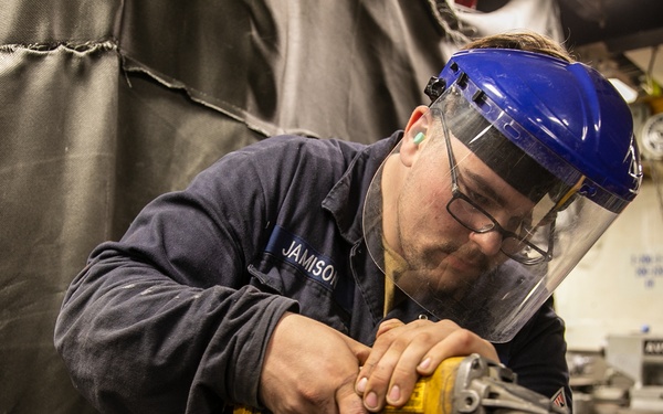 USS Mitscher (DDG 57) Sailor conducts machine shop maintenance